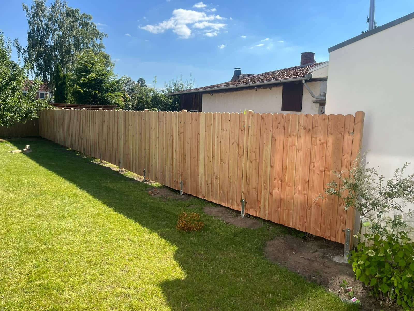 Holzzaun aus Rundspalieren als Sichtschutz im Garten